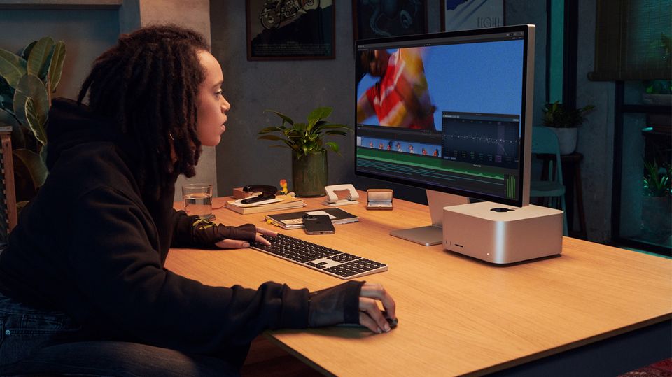Frau sitzt am Schreibtisch und benutzt einen Mac Studio