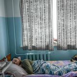 In einem metallenen Krankenhausbett liegt ein junger weißer Mann auf dem Bauch und schläft