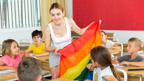 Eine Lehrerin zeigt ihrer Klasse eine Regenbogenflagge
