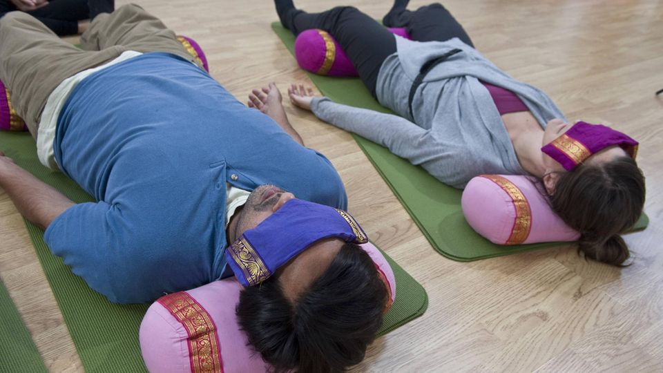 Yoga Nidra Yogaschüler liegen mit verdeckten Augen auf dem Boden