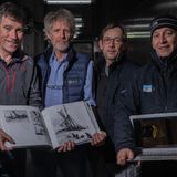 Vier Männer zeigen ein Buch und den Scan des Unterwasserroboters