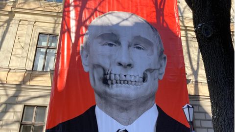 Ein großes Plakat mit Putin als Totenkopf hängt an einer Hausfassade