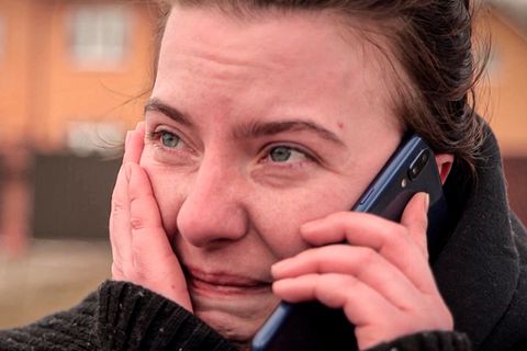 Eine weinende Frau telefoniert mit ihrem Smartphone.