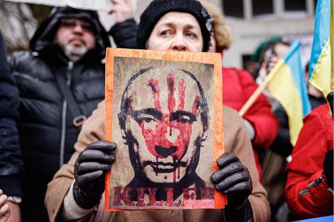 Eine Frau hält ein Foto mit einem Putin-Bild hoch, auf dem ein roter Handabdruck zu sehen ist
