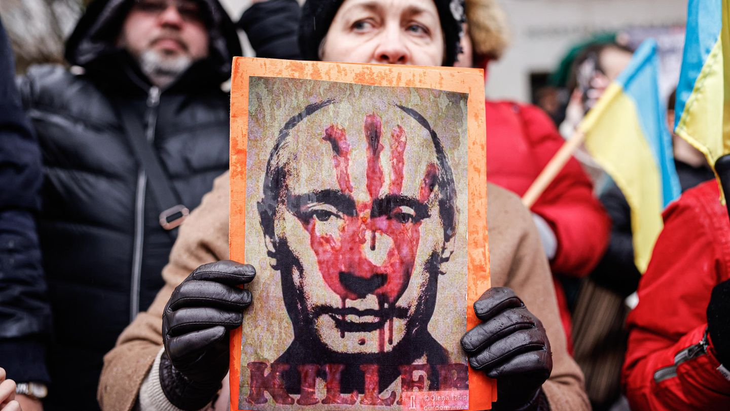 Eine Frau hält ein Foto mit einem Putin-Bild hoch, auf dem ein roter Handabdruck zu sehen ist