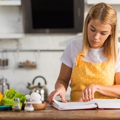 Vegetarisches Kochbuch Eine Frau liest in einem Kochbuch