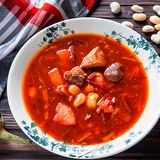 Traditioneller Borschtsch  Zutaten:  300 g fleischige Schweinerippchen, 1 mittelgroße Rote Bete, 1 große Karotte, 2 mittelgroße Kartoffeln, 100 g getrocknete Bohnen, 150 g Aubergine, 150 g Kohl, 2 EL Tomatenmark, 1 EL Kristallzucker, 2 Lorbeerblätter, 2 Knoblauchzehen, 2 EL Pflanzenöl (am besten Sonnenblumenöl), Schwarze Pfefferkörner, Salz, und gemahlener Pfeffer  Zubereitung:  1. Die Rote Bete waschen und anderthalb Stunden im Ofen backen (oder bis sie weich sind), abkühlen lassen, schälen und in Julienne schneiden oder mit einer Reibe zerkleinern. Klappt auch mit vorgekochter Roter Bete aus dem Supermarkt.  2. Die getrockneten Bohnen im kalten Wasser für eine Stunde einweichen. Danach aus dem Wasser nehmen.  3. Das Fleisch leicht salzen und zusammen mit dem Knoblauch, dem Lorbeerblatt und einigen Pfefferkörnern in eine ofenfeste Form geben. 20 Minuten bei 180 °C backen. Das Backen des Fleisches vor der Zubereitung der Brühe intensiviert den Geschmack der Suppe. Das Fleisch abkühlen lassen und in Stücke schneiden.  4. Die Karotte grob reiben, die Zwiebel und die Aubergine fein würfeln. Etwas Öl in einer Bratpfanne erhitzen und Karotte und Zwiebel etwa 2-3 Minuten anbraten. Fügen Sie die Aubergine und die Rote Bete hinzu und braten Sie alles für weitere 2 Minuten. Tomatenmark und Zucker dazugeben und weitere zwei Minuten garen.  5. Kartoffenl schälen und in mittelgroße Würfel schneiden. Die Kartoffeln in einen großen Topf geben und mit zwei Liter Wasser auffüllen. Dann das Fleisch dazugeben und für weitere fünf Minuten köcheln lassen.  6. Den fein geraspelten Kohl und die Bohnen dazugeben und für ca. 15 Minuten weiterkochen. Dann das restliche Gemüse dazugeben und für fünf Minuten garen. Salz und Pfeffer nach Geschmack. Ganz zum Schluss etwas zerdrückten Knoblauch dazugeben und vom Herd nehmen.