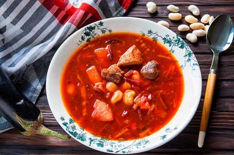 Traditioneller Borschtsch  Zutaten:  300 g fleischige Schweinerippchen, 1 mittelgroße Rote Bete, 1 große Karotte, 2 mittelgroße Kartoffeln, 100 g getrocknete Bohnen, 150 g Aubergine, 150 g Kohl, 2 EL Tomatenmark, 1 EL Kristallzucker, 2 Lorbeerblätter, 2 Knoblauchzehen, 2 EL Pflanzenöl (am besten Sonnenblumenöl), Schwarze Pfefferkörner, Salz, und gemahlener Pfeffer  Zubereitung:  1. Die Rote Bete waschen und anderthalb Stunden im Ofen backen (oder bis sie weich sind), abkühlen lassen, schälen und in Julienne schneiden oder mit einer Reibe zerkleinern. Klappt auch mit vorgekochter Roter Bete aus dem Supermarkt.  2. Die getrockneten Bohnen im kalten Wasser für eine Stunde einweichen. Danach aus dem Wasser nehmen.  3. Das Fleisch leicht salzen und zusammen mit dem Knoblauch, dem Lorbeerblatt und einigen Pfefferkörnern in eine ofenfeste Form geben. 20 Minuten bei 180 °C backen. Das Backen des Fleisches vor der Zubereitung der Brühe intensiviert den Geschmack der Suppe. Das Fleisch abkühlen lassen und in Stücke schneiden.  4. Die Karotte grob reiben, die Zwiebel und die Aubergine fein würfeln. Etwas Öl in einer Bratpfanne erhitzen und Karotte und Zwiebel etwa 2-3 Minuten anbraten. Fügen Sie die Aubergine und die Rote Bete hinzu und braten Sie alles für weitere 2 Minuten. Tomatenmark und Zucker dazugeben und weitere zwei Minuten garen.  5. Kartoffenl schälen und in mittelgroße Würfel schneiden. Die Kartoffeln in einen großen Topf geben und mit zwei Liter Wasser auffüllen. Dann das Fleisch dazugeben und für weitere fünf Minuten köcheln lassen.  6. Den fein geraspelten Kohl und die Bohnen dazugeben und für ca. 15 Minuten weiterkochen. Dann das restliche Gemüse dazugeben und für fünf Minuten garen. Salz und Pfeffer nach Geschmack. Ganz zum Schluss etwas zerdrückten Knoblauch dazugeben und vom Herd nehmen.