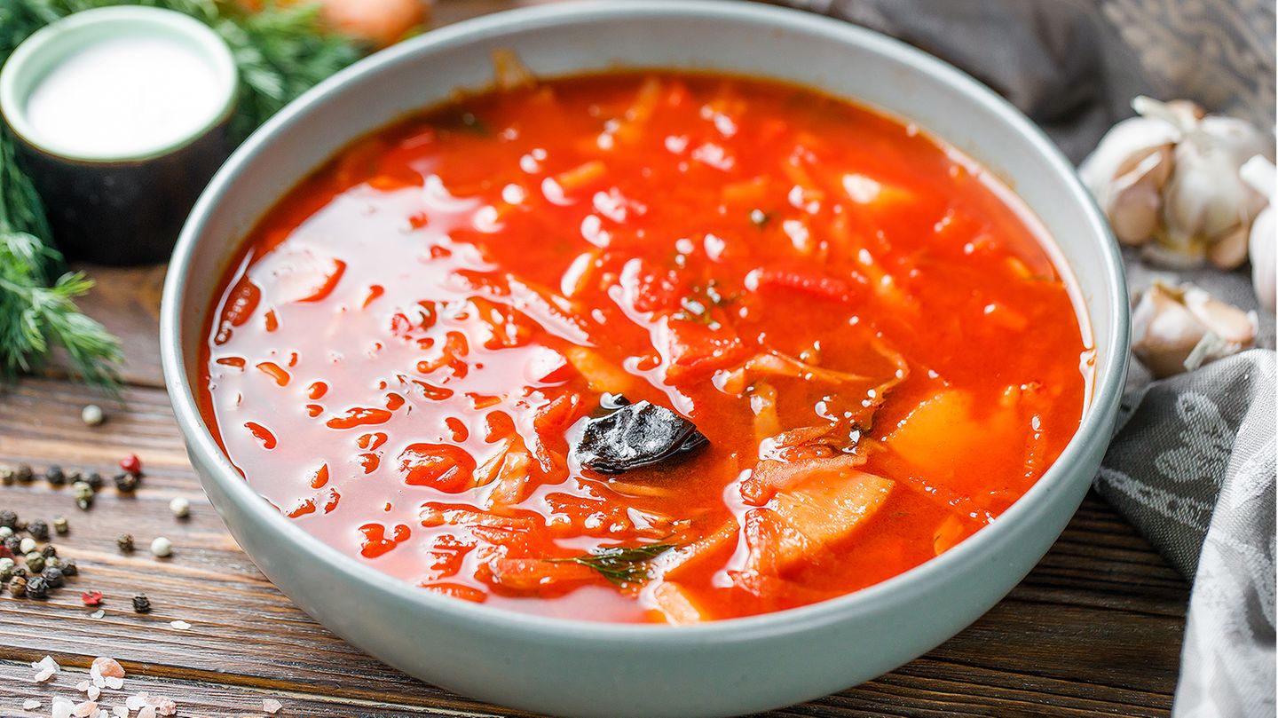 Ukrainischer Borschtsch mit Schweinerippchen  Zutaten:   400-500 g Schweinerippchen, 2 Rote Bete, 2 Tomaten, ¼ Selleriewurzel, ¼ Kohlkopf, 3-4 Kartoffeln, 1-2 Karotten, 1 Zwiebel, 2 Lorbeerblätter, 3 Gewürznelken, Piment, 1 Knoblauchzehe, 1 rote Paprika, 200 ml Tomatensaft, 30 g ungesalzene Butter, 2 EL Tomatenmark, Salz  Außerdem: Saure Sahne und gehackter Dill zum Abschmecken  Zubereitung:  1. Backofen auf 200°C vorheizen. Die Schweinerippchen in einer ofenfesten Form etwa 30 Minuten backen bis sich eine goldene Kruste bildet. In der Zwischenzeit die Selleriewurzel waschen und grob hacken. Es ist nicht nötig, sie zu schälen. Schneiden Sie die Karotten in Stücke von etwa der gleichen Größe wie die Selleriestücke. Die gebackenen Rippchen in einen großen Topf geben, etwa 3 Liter Wasser hinzufügen. Fügen Sie die Sellerie- und Karottenstücke und eine halbe ungeschälte Zwiebel hinzu. Zum Kochen bringen und bei mittlerer Hitze etwa 30 Minuten köcheln lassen.  2. Jetzt das Gemüse: Das macht jeden Borschtsch so aromatisch. Die rote Paprika würfeln. Die Tomaten und die andere Hälfte der Zwiebel fein würfeln. Die Butter in einer Pfanne erhitzen und das Gemüse dünsten, bis es weich wird. 200ml Tomatensaft und ca. 2 EL Tomatenmark dazugeben und weitere 5-7 Minuten garen. Die eine Rote Bete grob reiben und zum Gemüse hinzugeben. Weitere 3-4 Minuten kochen lassen. Die andere Rote Bete entsaften oder sehr fein reiben.  3. Das ganze Gemüse mit Piment und Lorbeerblättern in den Topf mit den Rippchen geben. Nach Geschmack salzen.  4. Kartoffeln waschen und schälen, grob Würfeln und in den Topf geben. Knoblauchzehen halbieren und auch dazugeben.  5. Den Kohl in Streifen schneiden und beiseite stellen, erst ganz zum Schluss wird er in den Borschtsch gegeben.  6. Sobald alle Zutaten weich sind, den zerkleinerten Kohl in den Topf geben. 5 weitere Minuten garen und den Borschtsch vom Herd nehmen. Lassen Sie die Suppe mindestens eine halbe Stunde ruhen, bevor Sie sie mit saurer Sahne und fein gehacktem Dill servieren. Bewahren Sie den Borschtsch im Kühlschrank auf und denken Sie daran, dass er über Nacht noch köstlicher wird.