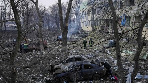 Ukrainische Rettungskräfte gehen an einer durch einen Angriff beschädigten Geburtsklinik in Mariupol vorbei