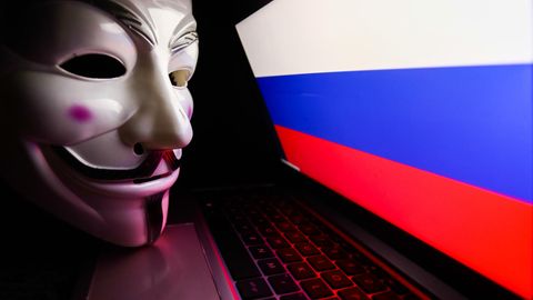 Die für Anonymous typische Maske liegt auf einem Laptop, der die russische Flagge zeigt