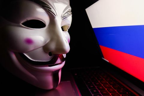 Die für Anonymous typische Maske liegt auf einem Laptop, der die russische Flagge zeigt