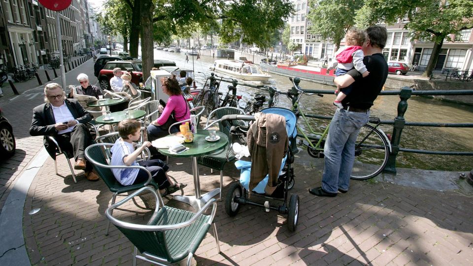 Menschen in einem Straßencafé an einer Gracht in Amsterdam