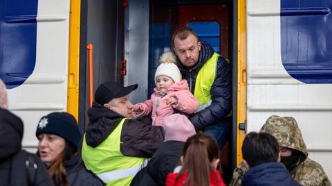 Zwei Männer heben ein Kleinkind am Bahnhof von Lwiw, Ukraine, in einen Eisenbahnwaggon