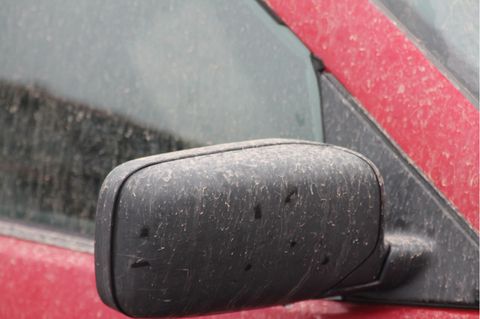 Der Außenspiegel eines Autos ist mit rötlichen Tropfen bedeckt