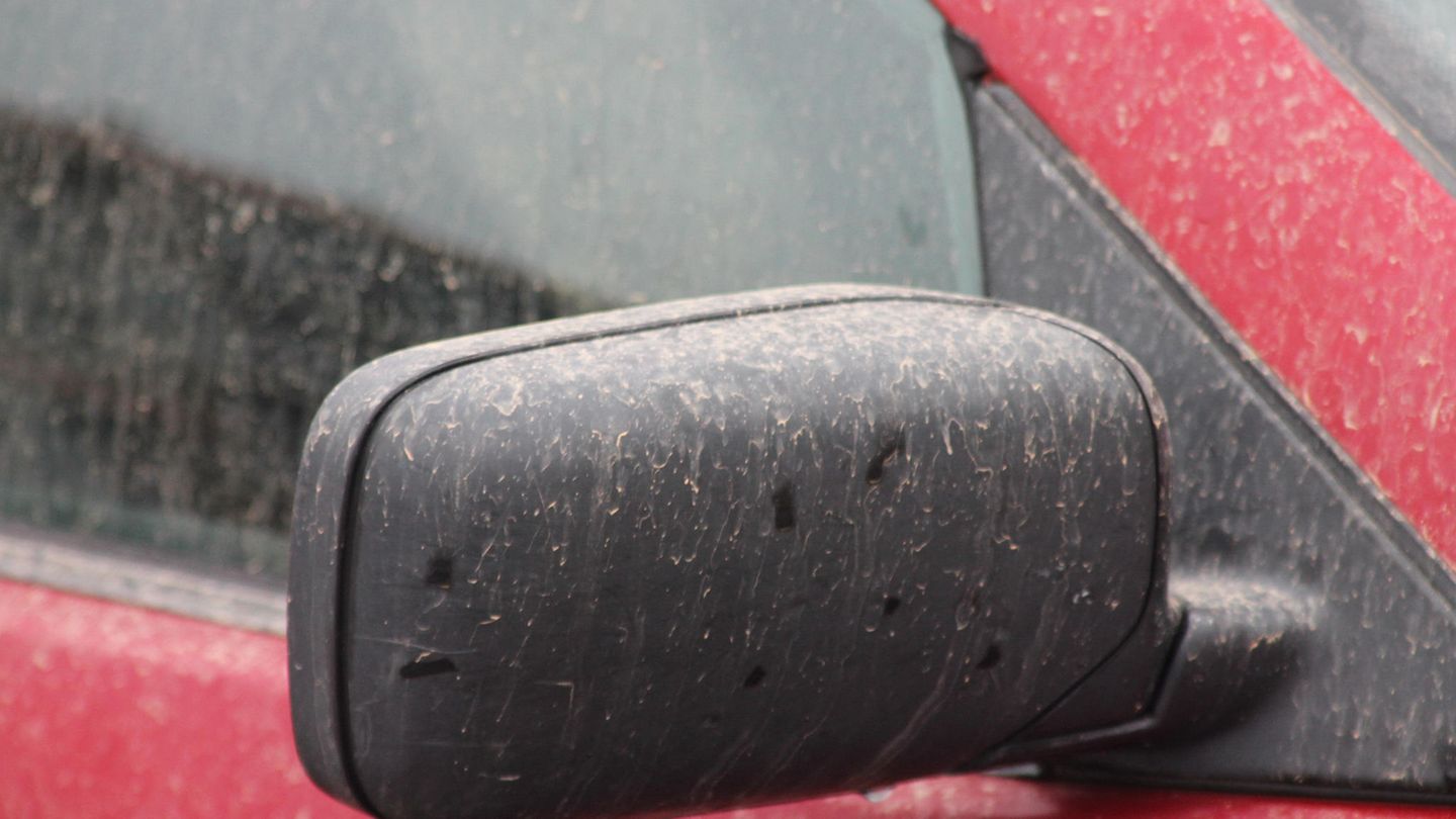 Der Außenspiegel eines Autos ist mit rötlichen Tropfen bedeckt