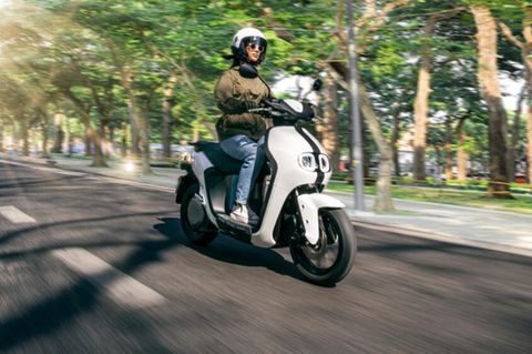 Eine Frau fährt mit einem Yamaha Neo's auf einer Straße