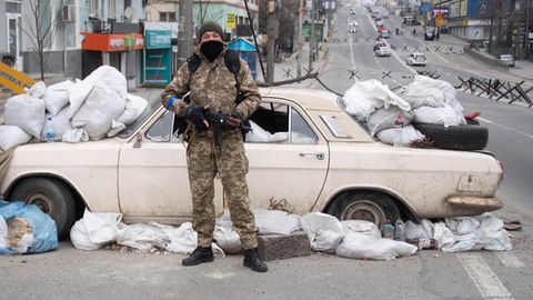In Kiew haben die Soldaten überall Straßensperren errichtet, so wie hier mit einem Auto, Sandsäcken und Müll. Im Hintergrund sind weitere Sperren zu erkennen, die russische Panzer aufhalten sollen