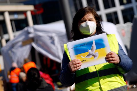 Eine ehrenamtliche Helferin empfängt Geflüchtete aus der Ukraine in Köln