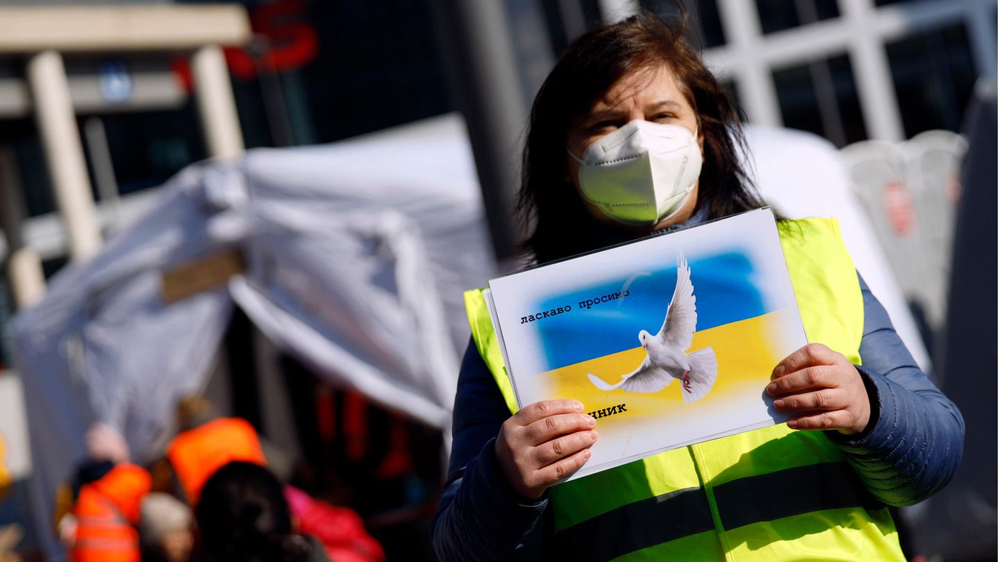Eine ehrenamtliche Helferin empfängt Geflüchtete aus der Ukraine in Köln