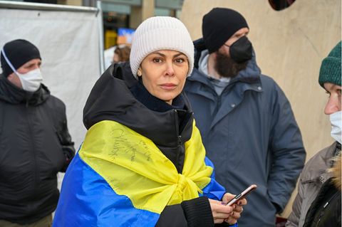 Natalia Klitschko mit Mütze, Handy und einer Ukraine-Flagge um die Schultern