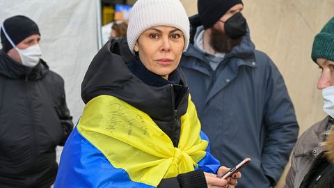 Natalia Klitschko mit Mütze, Handy und einer Ukraine-Flagge um die Schultern