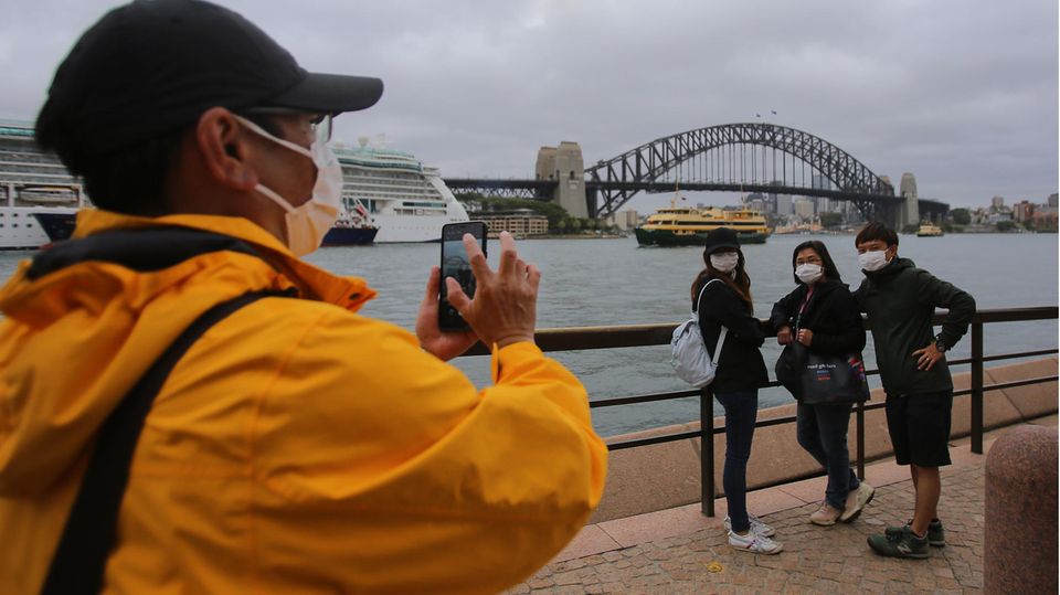 Tourists take a photo in front of a port bridge in Australia