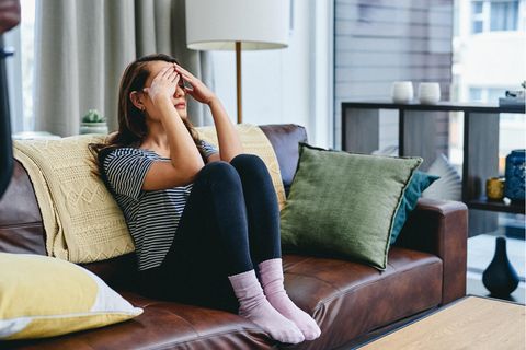 Erschöpfte Frau sitzt auf dem Sofa