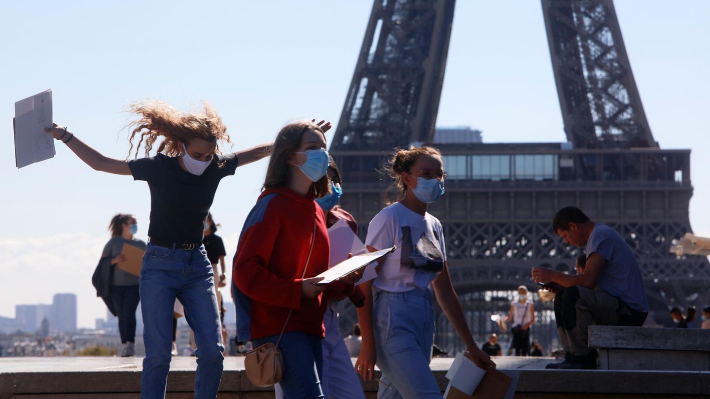 Passanten laufen vor dem Eiffelturm in Paris.