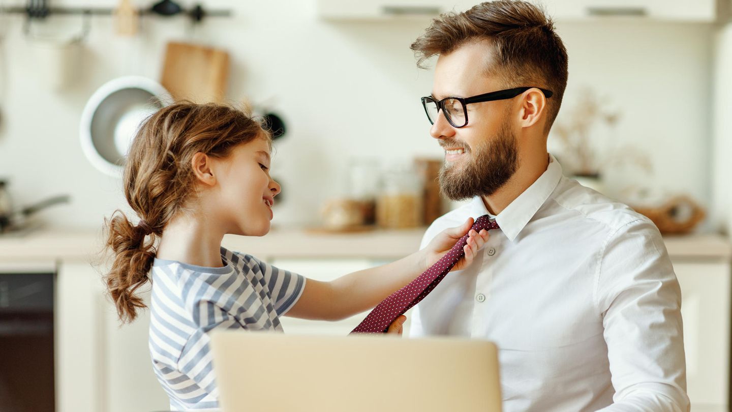Ein kleines Mädchen zieht den Vater an der Krawatte