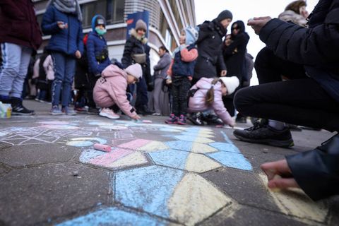 Kinder, die mit ihren Angehörigen aus der Ukraine geflohen sind, malen mit Kreide auf den Boden