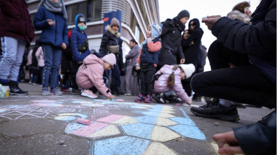 Kinder, die mit ihren Angehörigen aus der Ukraine geflohen sind, malen mit Kreide auf den Boden