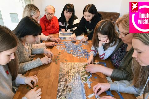 Eine ukrainische Familie sitzt in einer deutschen Ferienwohnung bei einem Puzzlespiel