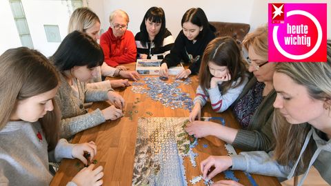 Eine ukrainische Familie sitzt in einer deutschen Ferienwohnung bei einem Puzzlespiel
