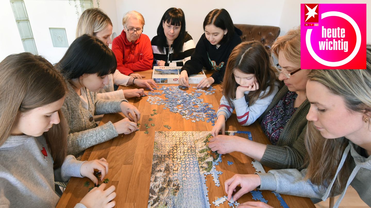 Eine ukrainische Familie sitzt in einer deutschen Ferienwohnung bei einem Puzzlespiel