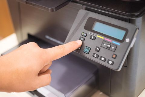 Eine Person drückt einen Knopf auf einem Drucker