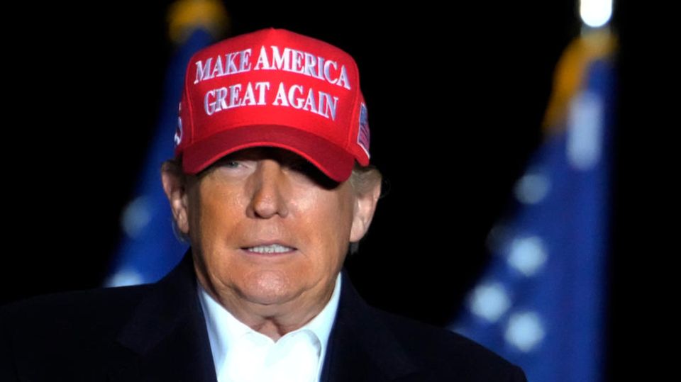 Donald Trump mit roter MAGA-Mütze vor US-Flagge