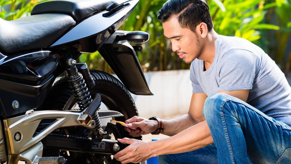 Ein junger Mann wartet ein Motorrad