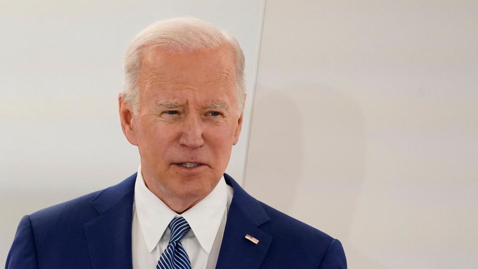 Joe Biden Ein alter weißer Mann in blauem Anzug, weißem Hemd und blau gemusterter Krawatte gestikuliert hinter einem Rednerpult