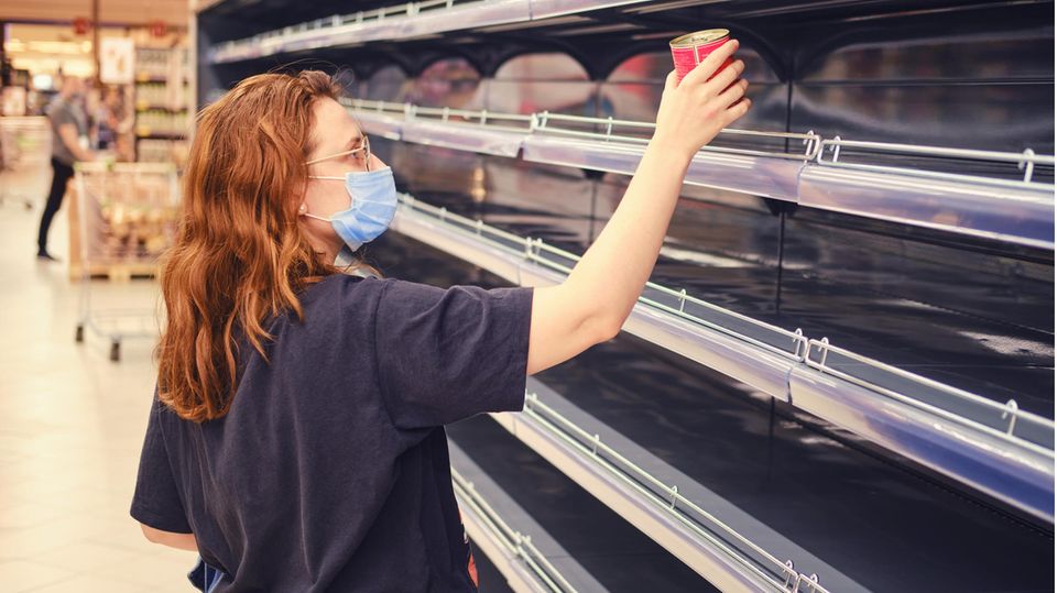 Eine junge Frau vor einem leeren Supermarktregal