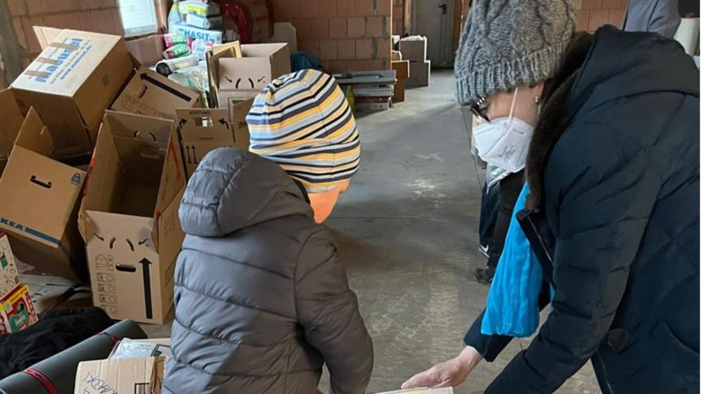 Ukrainischer Verein hilft Eine Frau und ein Junge packen bei Hilfslieferungen des ukrainischen Vereins mit an