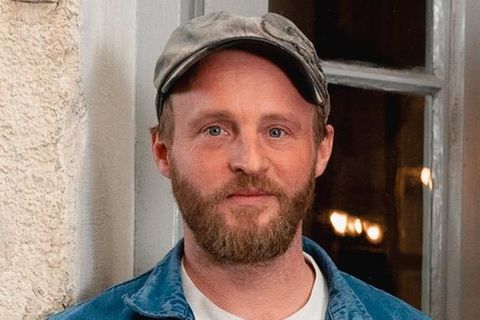 Schauspieler Florian Brückner lehnt mit den Händen in der Hosentasche an einer Hauswand
