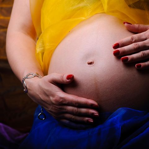Frau streichelt sich mit ihren Händen über den schwangeren Bauch