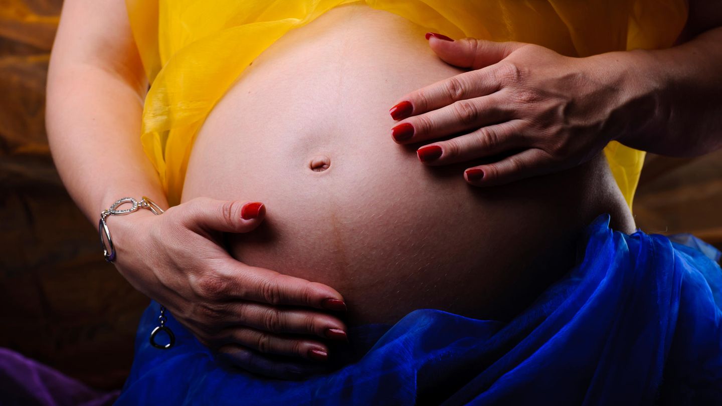 Bodyshaming Schwangerschaft Frau streichelt sich mit ihren Händen über den schwangeren Bauch