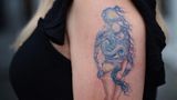 Auf dem Oberarm einer Frau wird in einem Tattoo aus zwei Kunstwerken von Botticelli und van Gogh eines