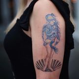 Auf dem Oberarm einer Frau wird in einem Tattoo aus zwei Kunstwerken von Botticelli und van Gogh eines