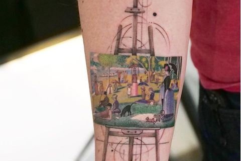 Ein Gemälde auf einer Staffelei zeigt Menschen im Park. Es steht auf einer Staffelei und ist ein Tattoo auf einem Arm.