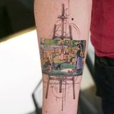 Ein Gemälde auf einer Staffelei zeigt Menschen im Park. Es steht auf einer Staffelei und ist ein Tattoo auf einem Arm.