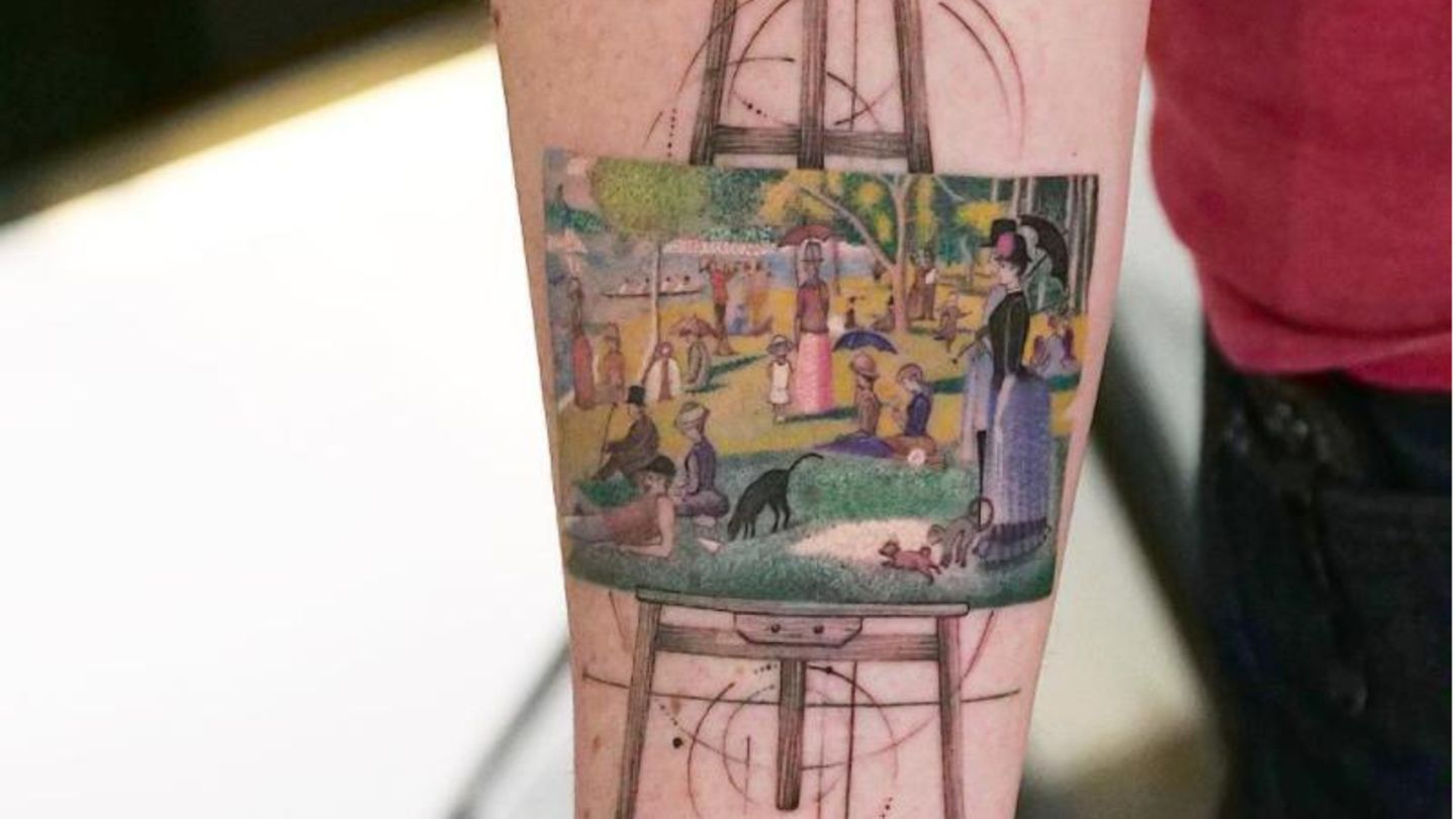 Ein Gemälde auf einer Staffelei zeigt Menschen im Park. Es steht auf einer Staffelei und ist ein Tattoo auf einem Arm. Ein Gemälde auf einer Staffelei zeigt Menschen im Park. Es steht auf einer Staffelei und ist ein Tattoo auf einem Arm.