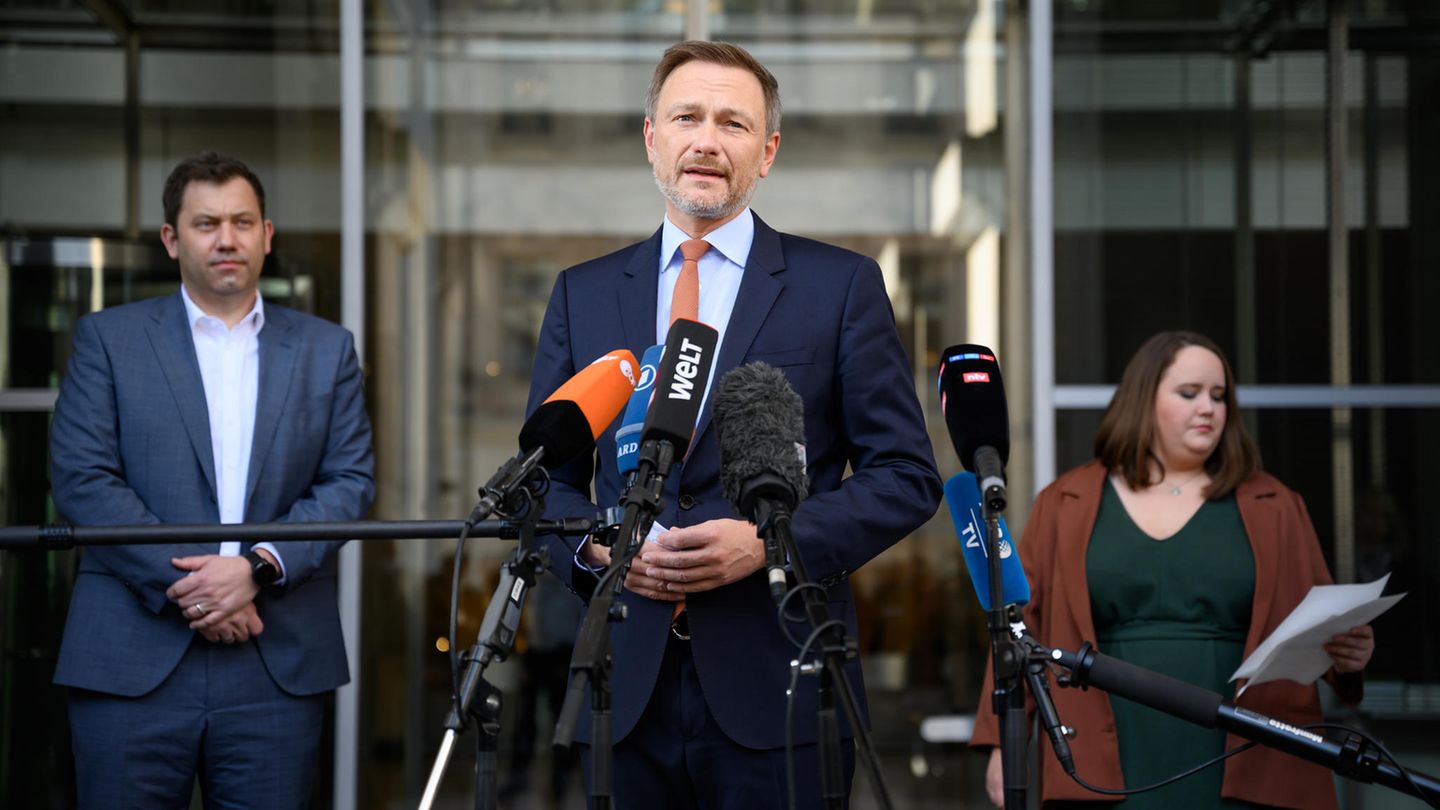 Christian Linder steht im Vordergrund und spricht in ein Mikrofo